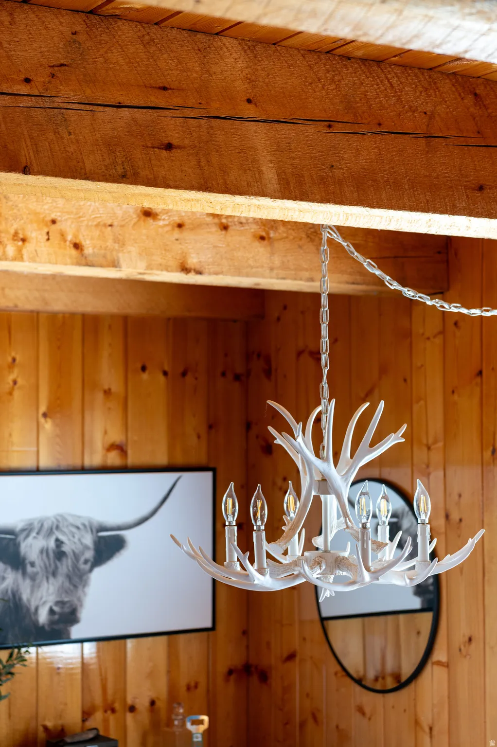 Exposed wood beams, wood paneling, and an antler-style chandelier