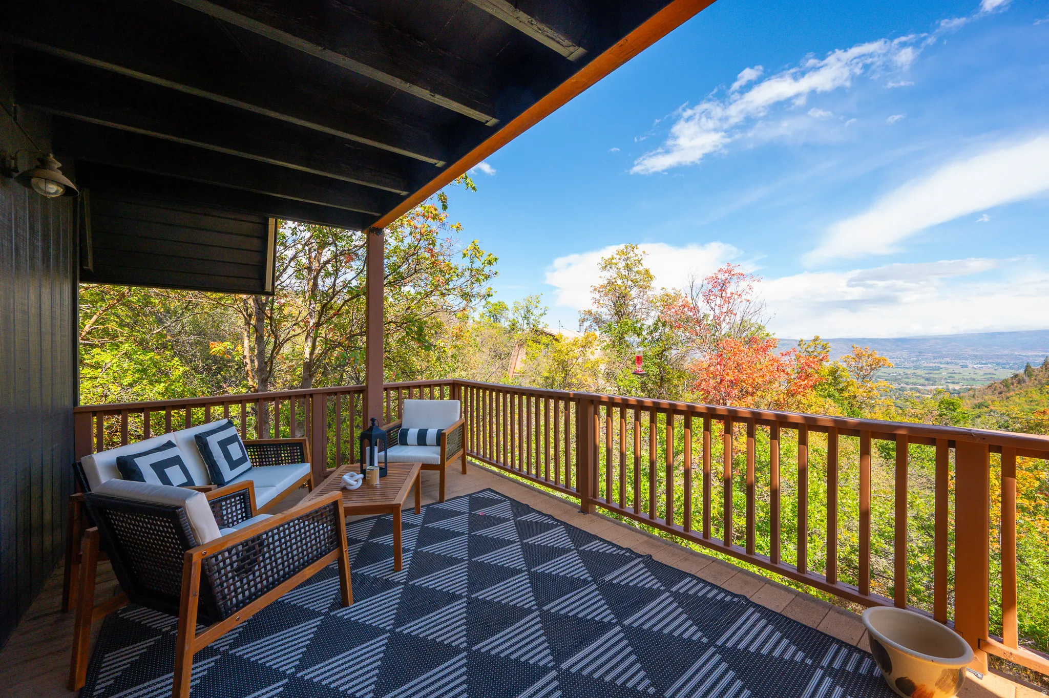 Expansive outdoor deck featuring wood flooring, wood railing, and a dark-painted overhead structure