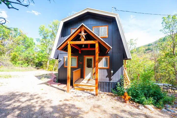 Gable roofline with dark vertical siding, wood-framed windows, and a covered porch