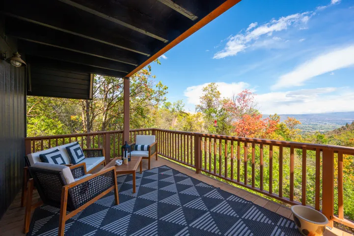 Expansive outdoor deck featuring wood flooring, wood railing, and a dark-painted overhead structure