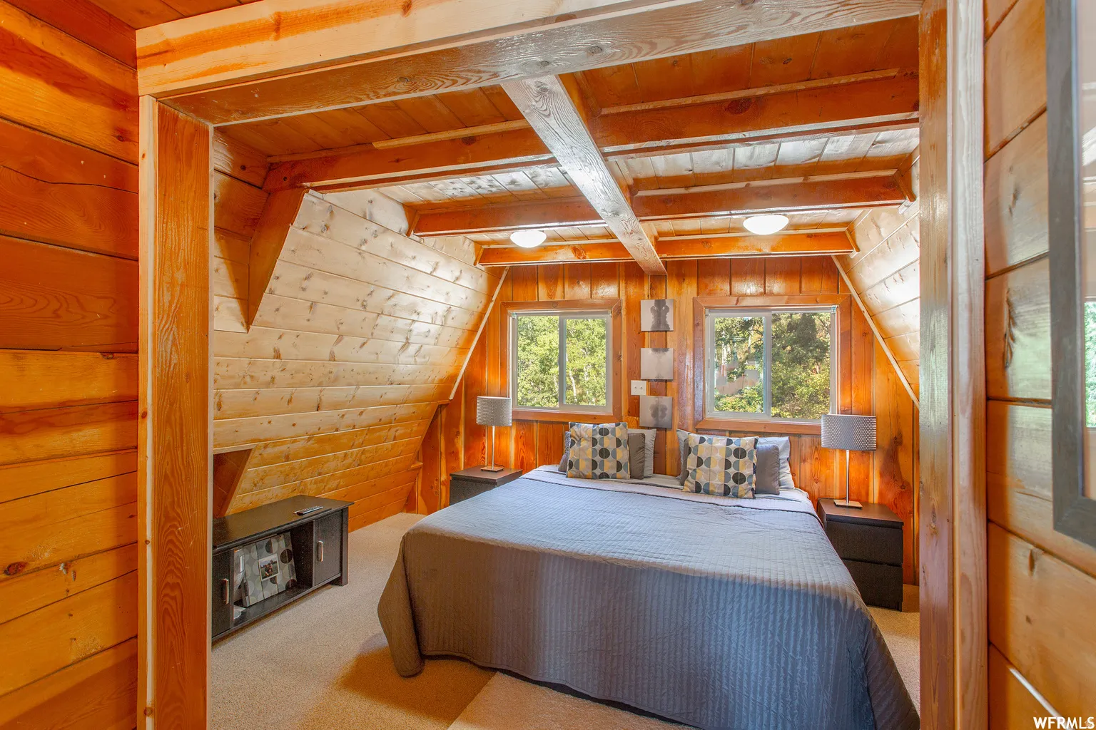 Wood-paneled room featuring exposed ceiling beams and two windows