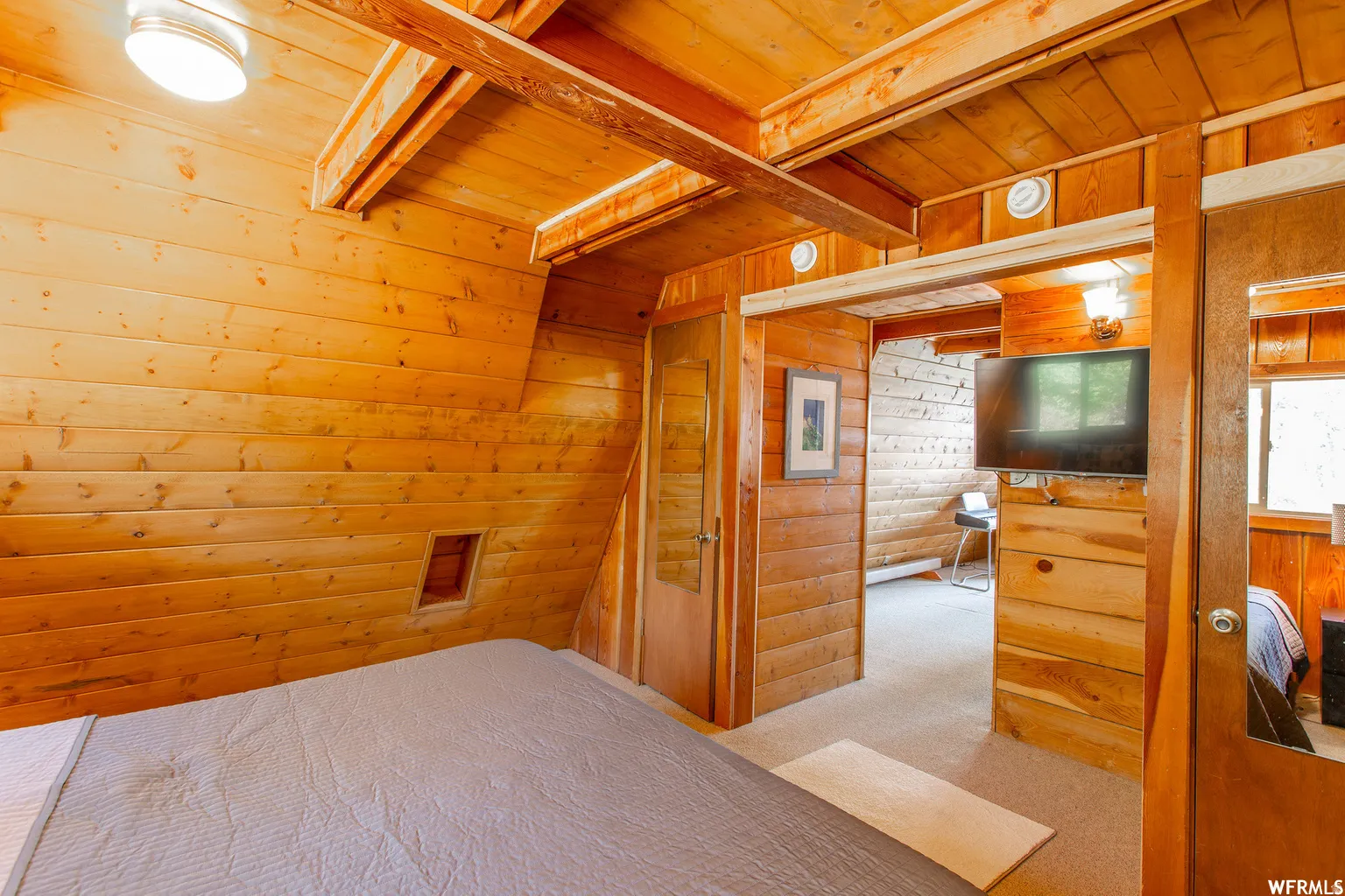 Wood plank walls, wood beam ceiling, and wood flooring visible through the doorway