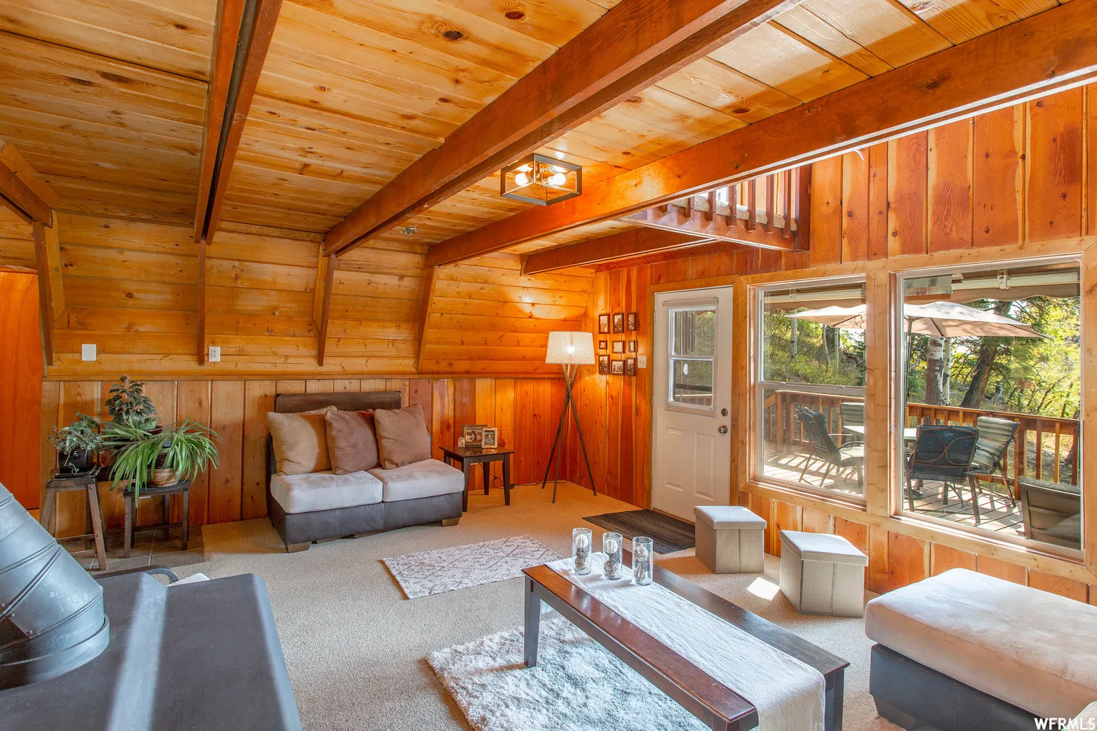 Vaulted wood-paneled ceiling, exposed wood beams, wood-paneled walls, built-in hearth, and expansive windows