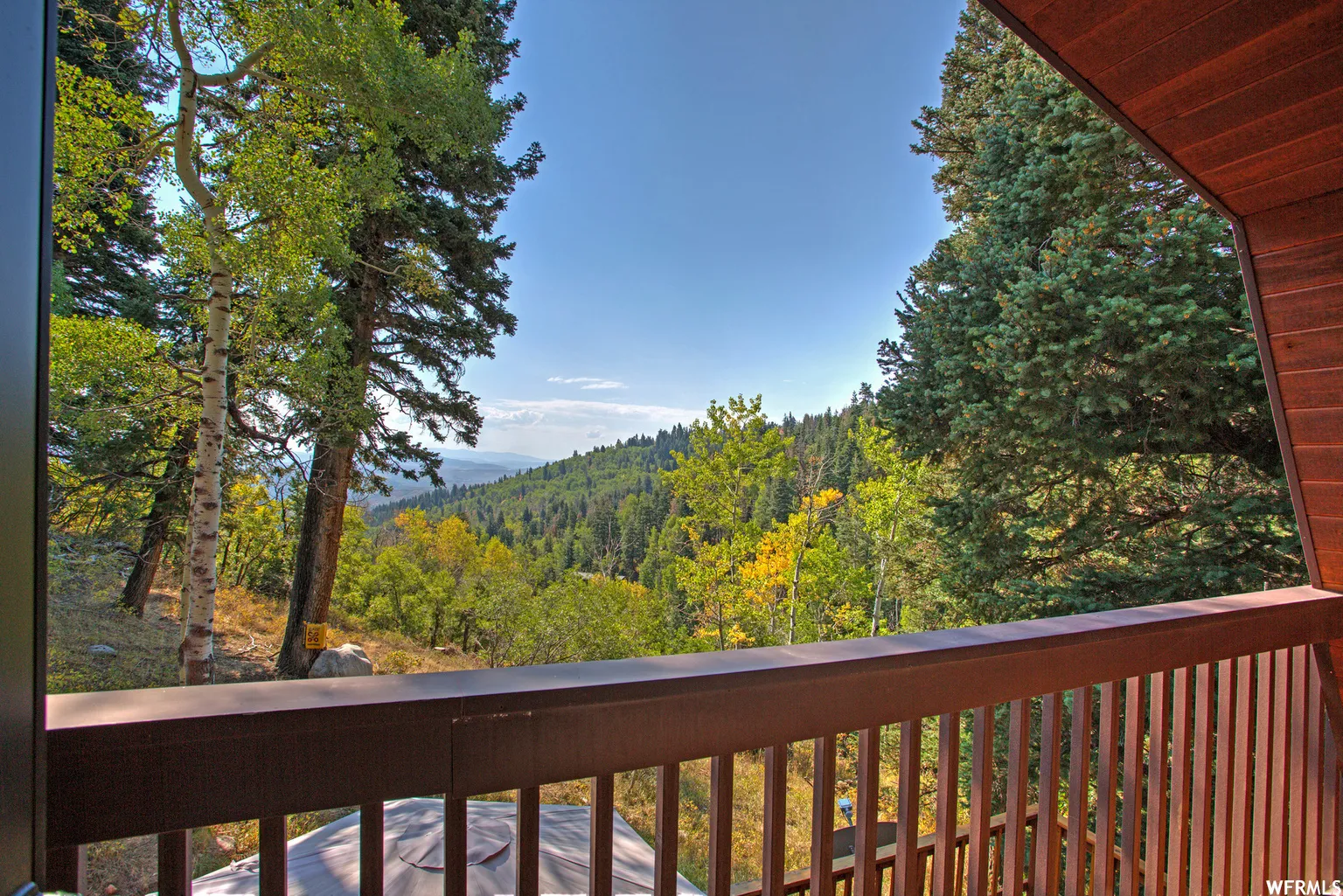 Exterior balcony featuring a wood-finish railing and vertical balusters