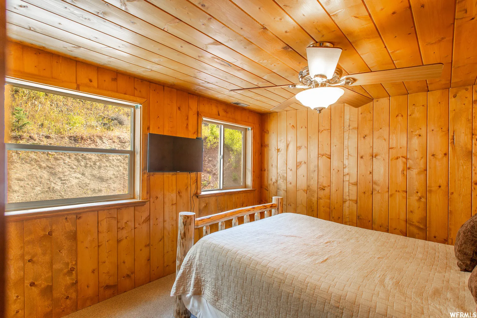Wood-paneled walls and ceiling, dual windows, and ceiling fan with integrated lighting