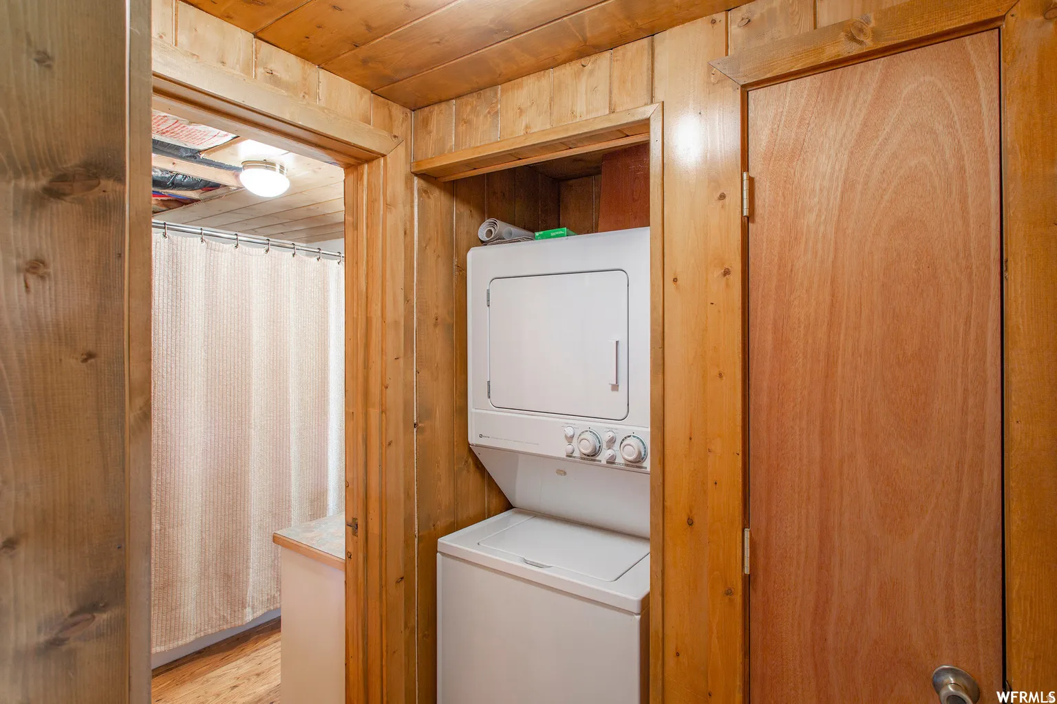 Wood paneling throughout, stacked washer and dryer, wood-finish flooring, built-in overhead lighting