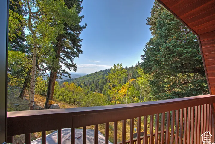 Exterior balcony featuring a wood-finish railing and vertical balusters