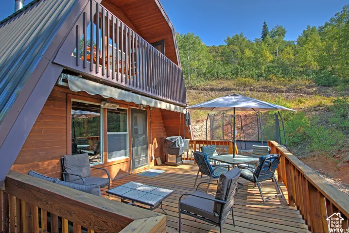 Expansive wood deck with a privacy railing, featuring a retractable awning and a second-story balcony