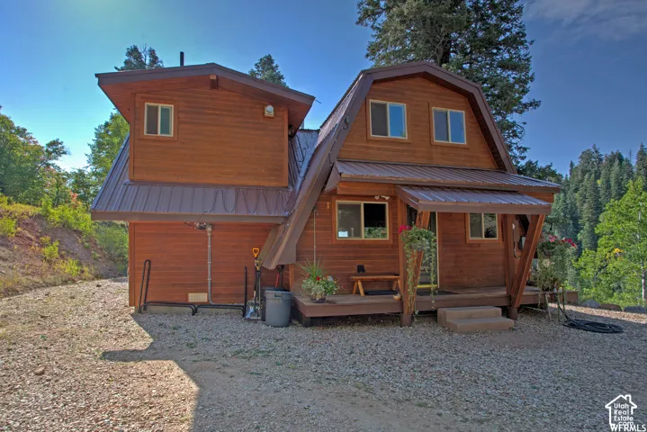 Wood-sided dwelling with a brown metal roof, featuring multiple windows and an inviting covered porch