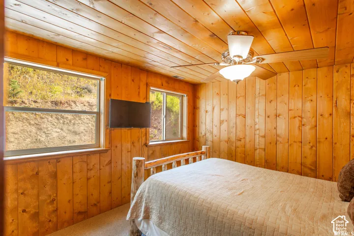 Wood-paneled walls and ceiling, dual windows, and ceiling fan with integrated lighting