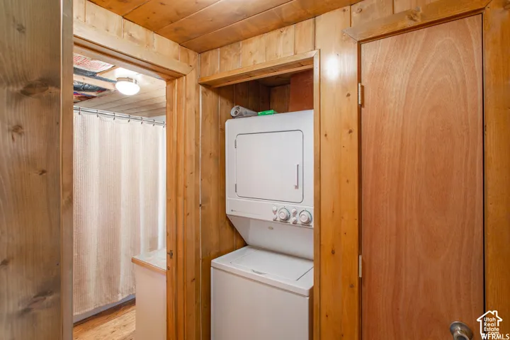 Wood paneling throughout, stacked washer and dryer, wood-finish flooring, built-in overhead lighting