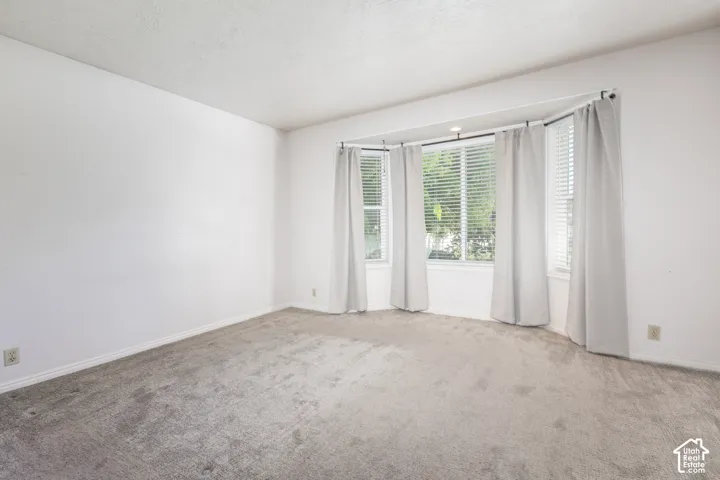 Bay window with blinds, recessed lighting, and grey carpet flooring