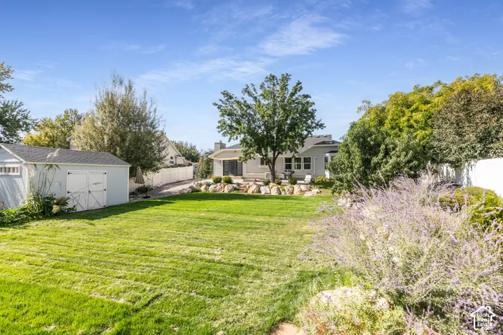 Spacious backyard with a vibrant lawn, mature trees, and a detached storage shed