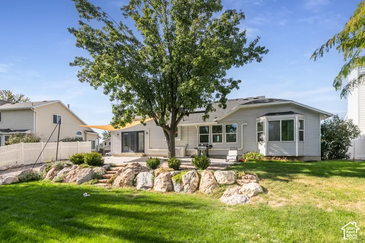 Expansive backyard featuring a manicured lawn, stone retaining wall, and a mature tree