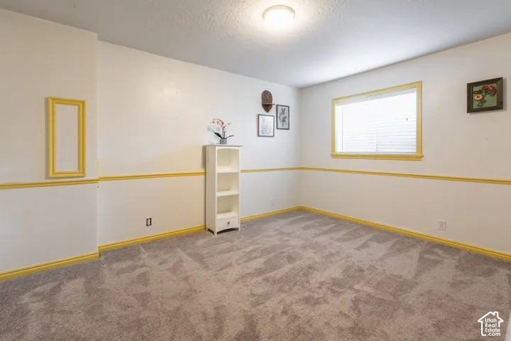 Spacious bonus room featuring neutral two-tone wall treatment with coordinating gold trim, plush carpet flooring, recessed ceiling lighting, and multiple windows providing natural illumination