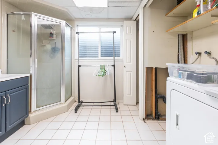 White tile flooring complemented by a corner shower enclosure and a vanity with blue cabinetry