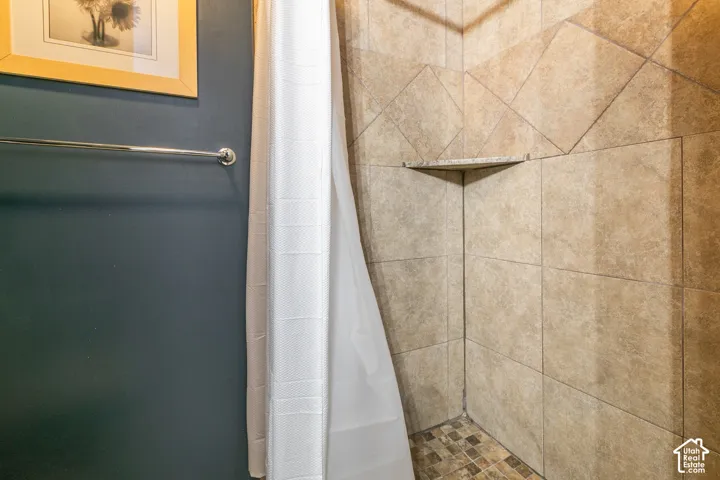 Tiled shower enclosure featuring a corner shelf and mosaic tile flooring