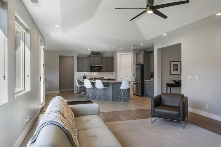 Open-concept living area featuring a vaulted ceiling with a ceiling fan, recessed lighting, and large windows