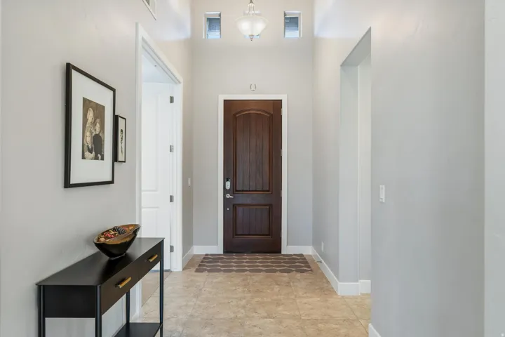 Entryway with light-toned tile flooring, a dark wood-finish door, and recessed niches