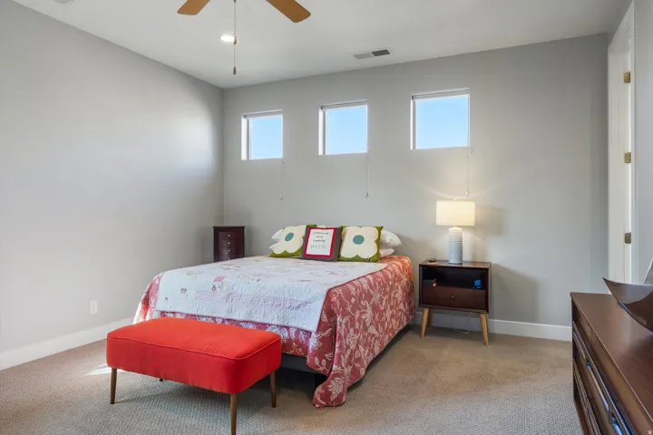 Light gray walls with three transom windows, a wood-finish ceiling fan, and carpeted flooring