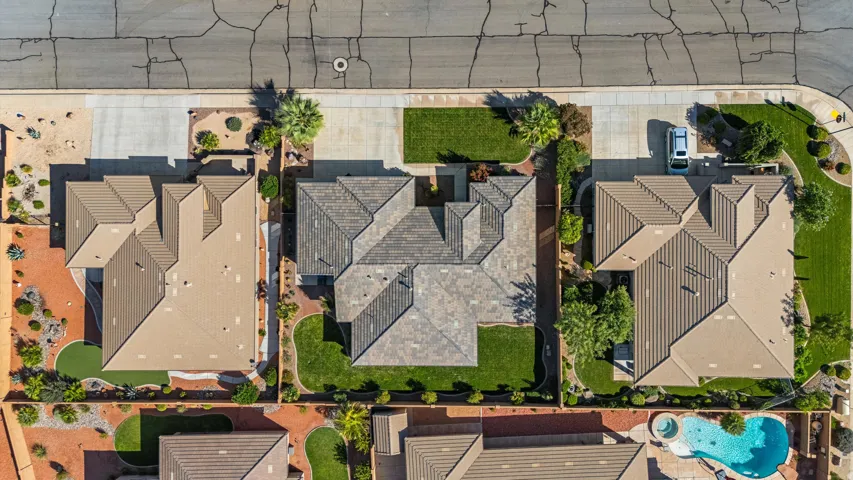 Aerial perspective showcasing a tiled roof, manicured lawn, paved driveway, and surrounding landscaping