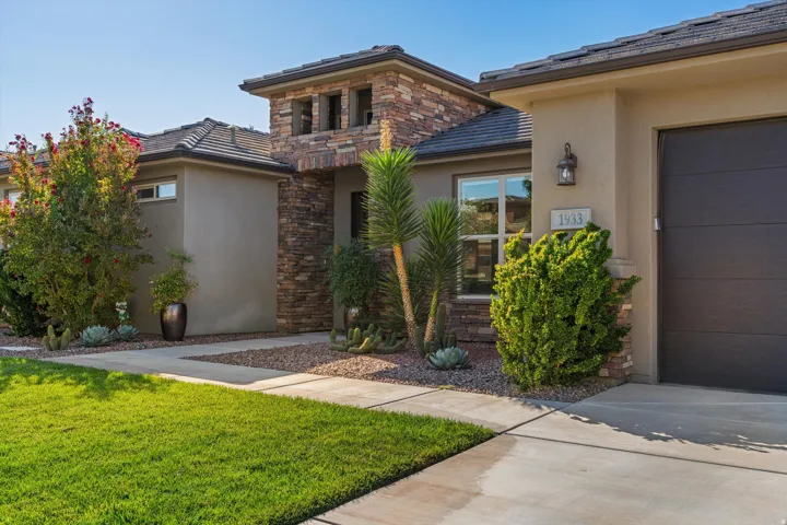 Stucco exterior with stone accents, tile roof, and a dark-toned garage door