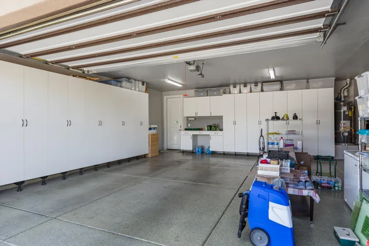 Built-in white cabinetry, integrated workbench area, and concrete flooring