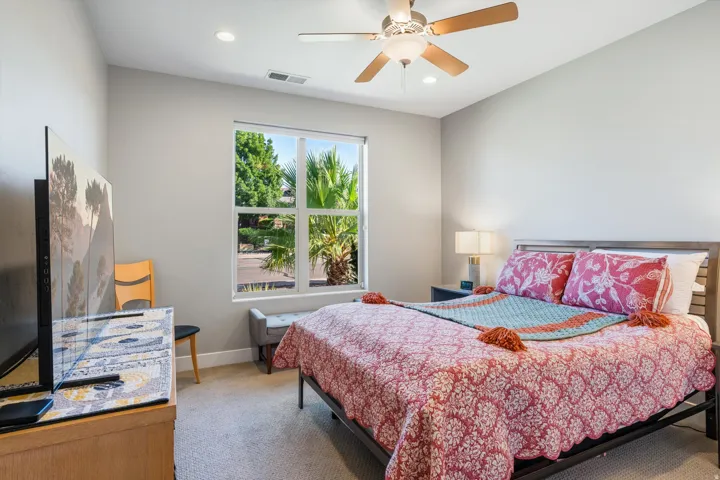 Recessed lighting, ceiling fan with light fixture, large window, wood-finish bed frame, and upholstered bench