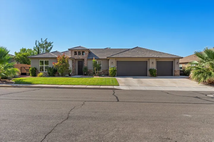 Contemporary exterior with a stone and stucco facade, a three-car garage, a concrete driveway, and a manicured front lawn