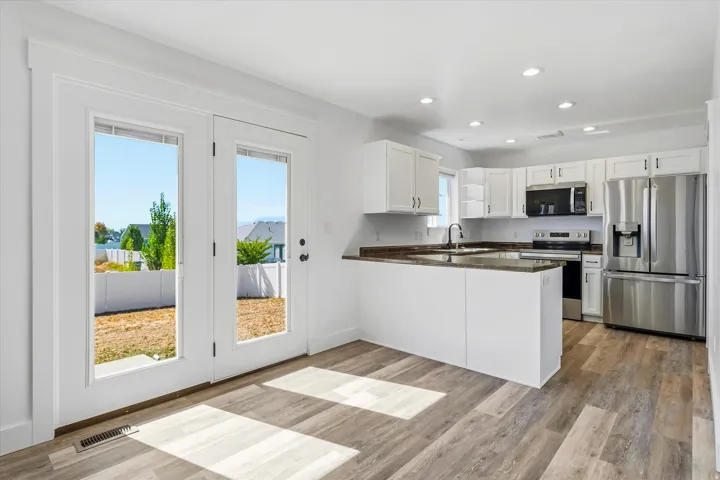 Open-concept kitchen with white cabinetry, stainless steel appliances, and hard flooring