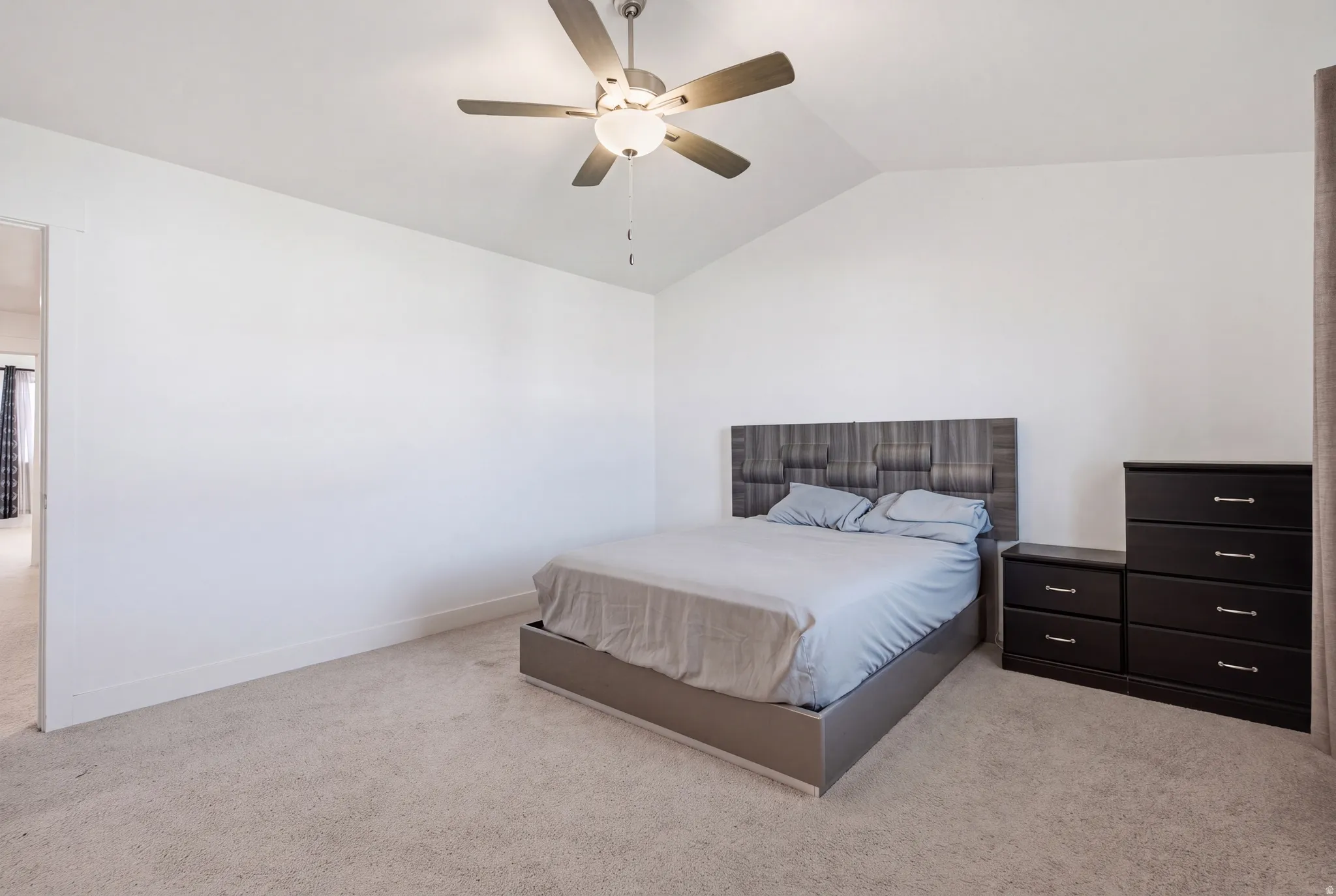 Vaulted ceiling, ceiling fan with integrated lighting, carpeted flooring, and white painted walls