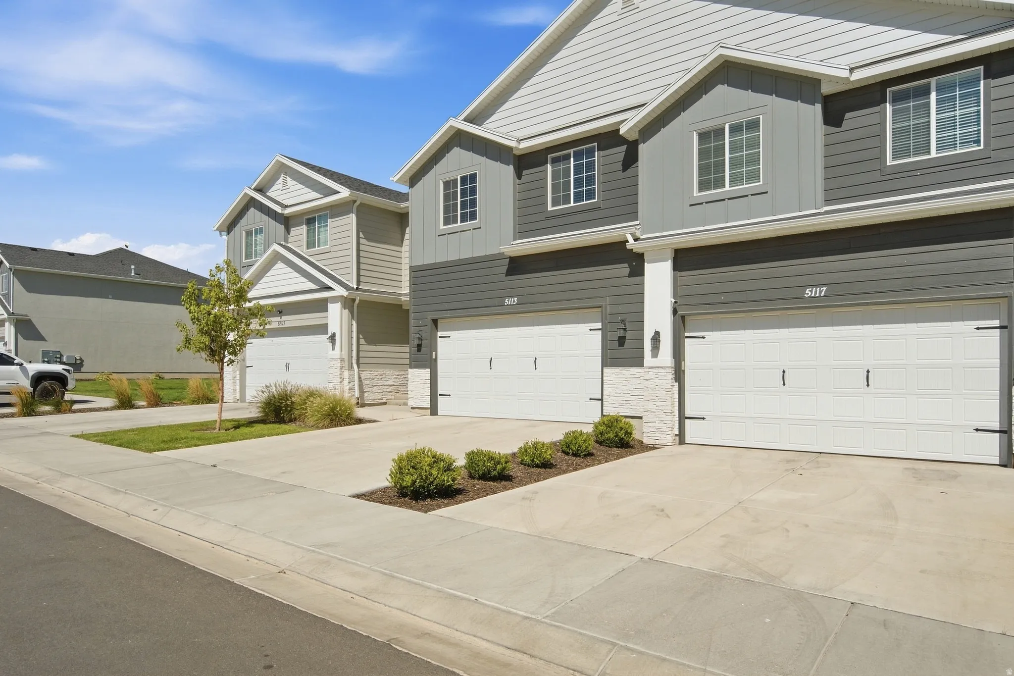 Modern exterior featuring gray siding, white trim, multiple windows, and a two-car garage