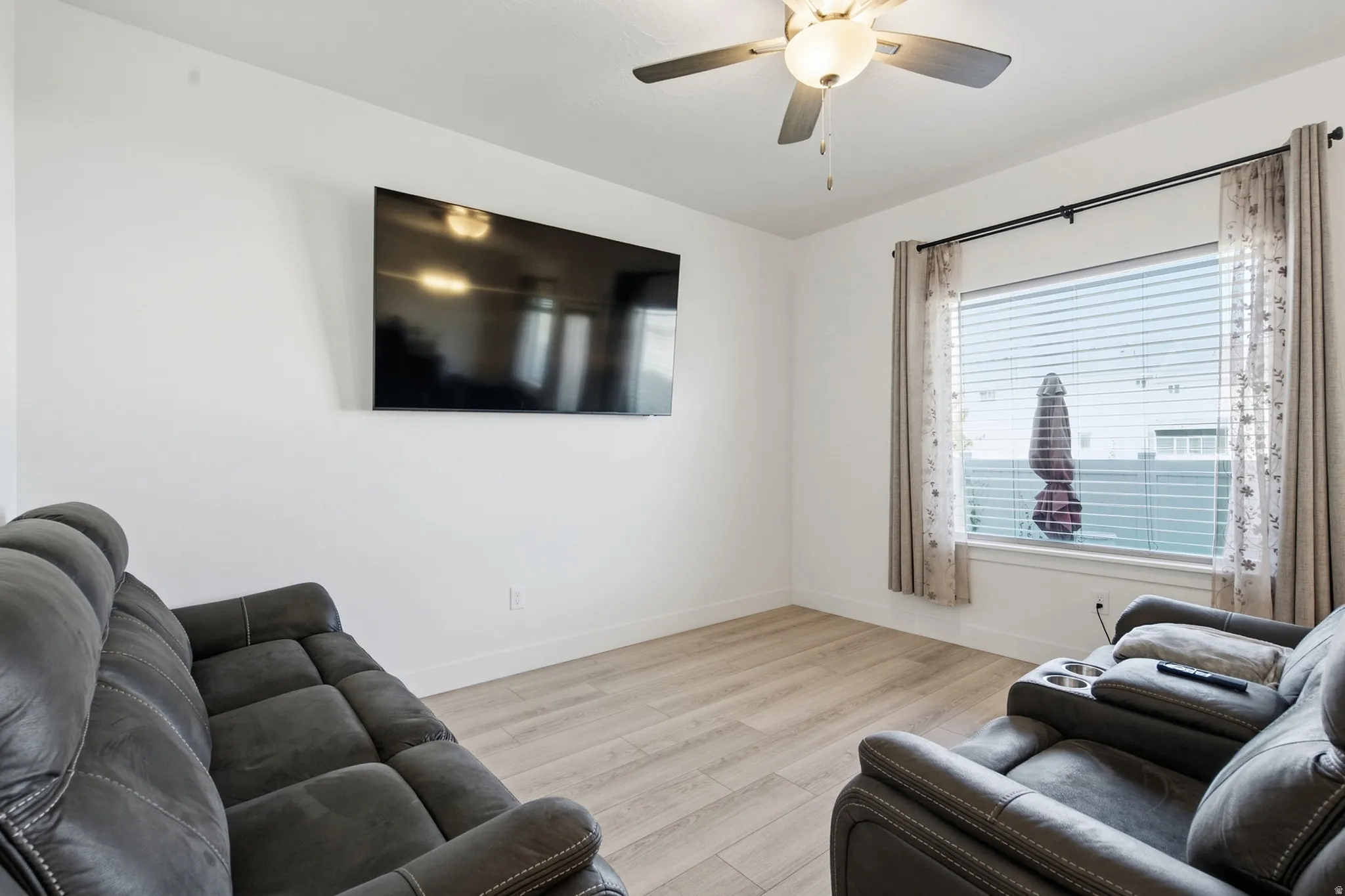 Recessed window with horizontal blinds, wood-finish flooring, ceiling fan with integrated lighting, and white walls