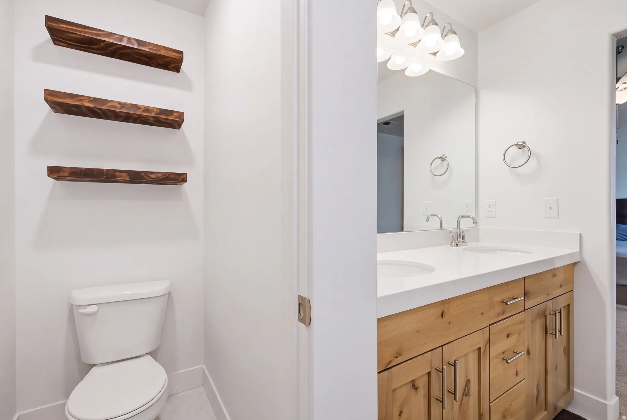 Dual vanity with undermount sinks, light-toned wood-finish cabinetry, and a large mirror