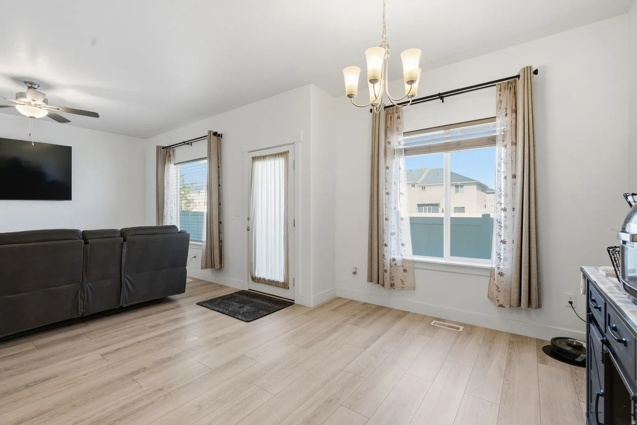 Spacious room featuring wood-finish flooring, a contemporary ceiling fan, and a multi-light chandelier