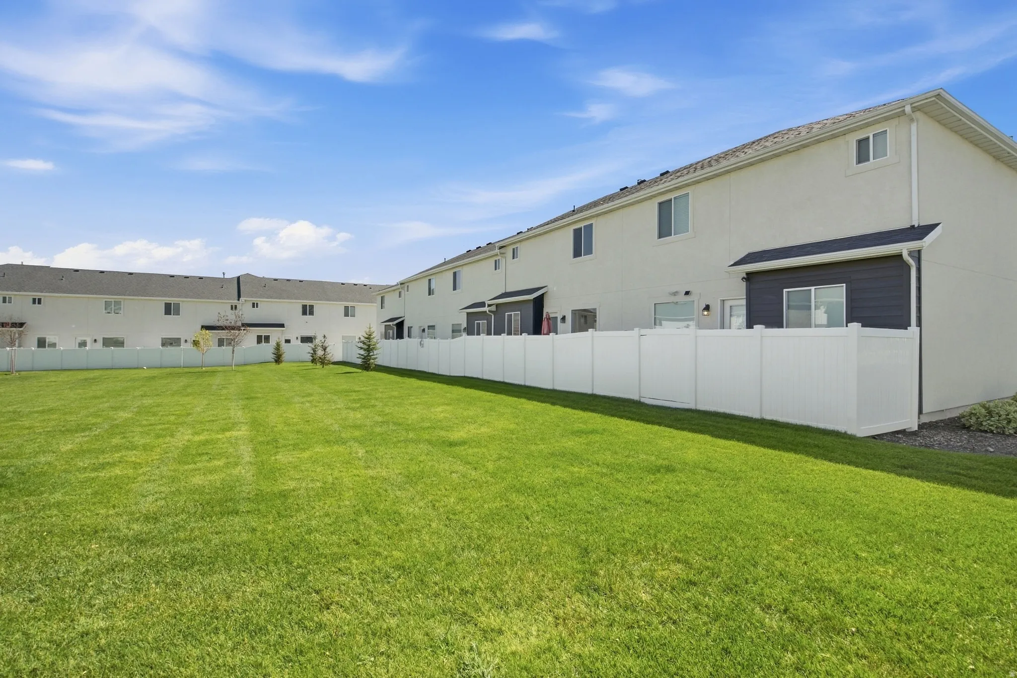 Expansive grassy area with a white privacy fence