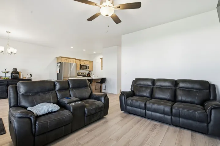 Open-concept living area with light wood-finish flooring, a ceiling fan, and recessed lighting