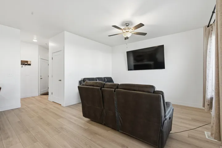 Wood-finish flooring throughout, bright white walls, and a ceiling fan with integrated lighting