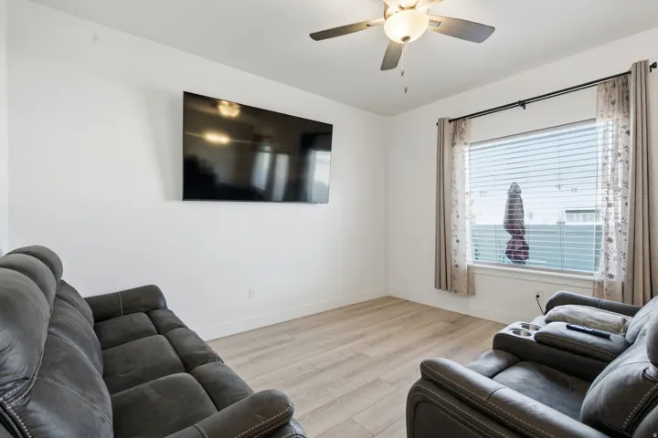 Recessed window with horizontal blinds, wood-finish flooring, ceiling fan with integrated lighting, and white walls