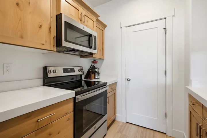 Stainless steel range with a built-in microwave, light wood-finish cabinetry, and white countertops