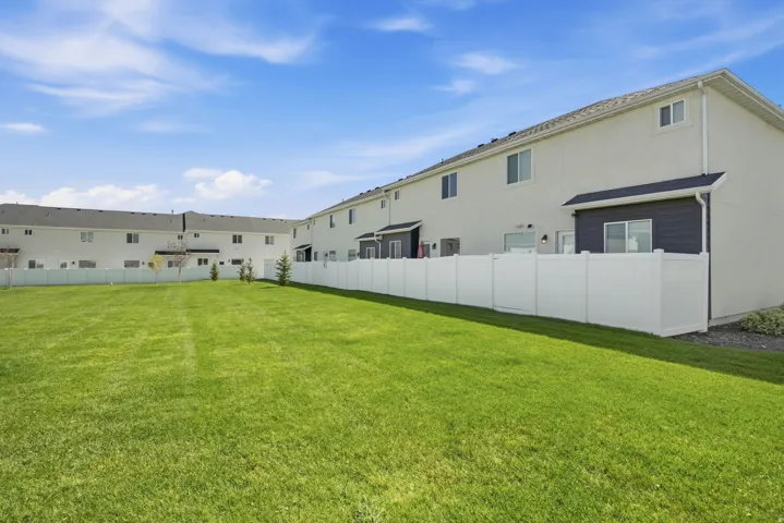 Expansive grassy area with a white privacy fence