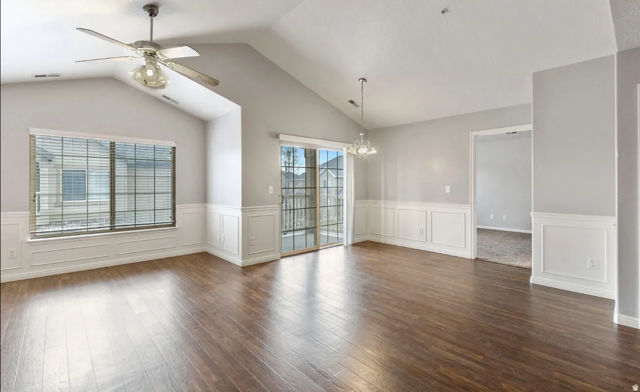 Vaulted ceilings with a ceiling fan, wood-finish flooring, wainscoting, and a sliding glass door to exterior