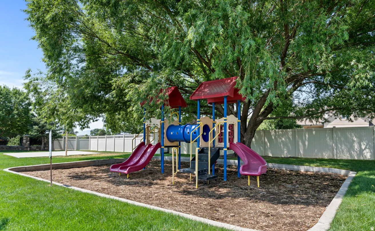 Playground area featuring a multi-level structure with two slides, a tunnel, and a climbing element