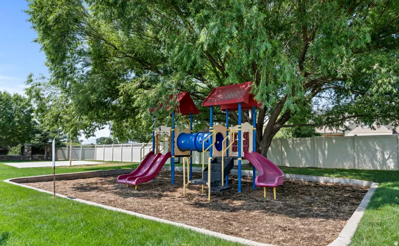 Playground area featuring a multi-level structure with two slides, a tunnel, and a climbing element