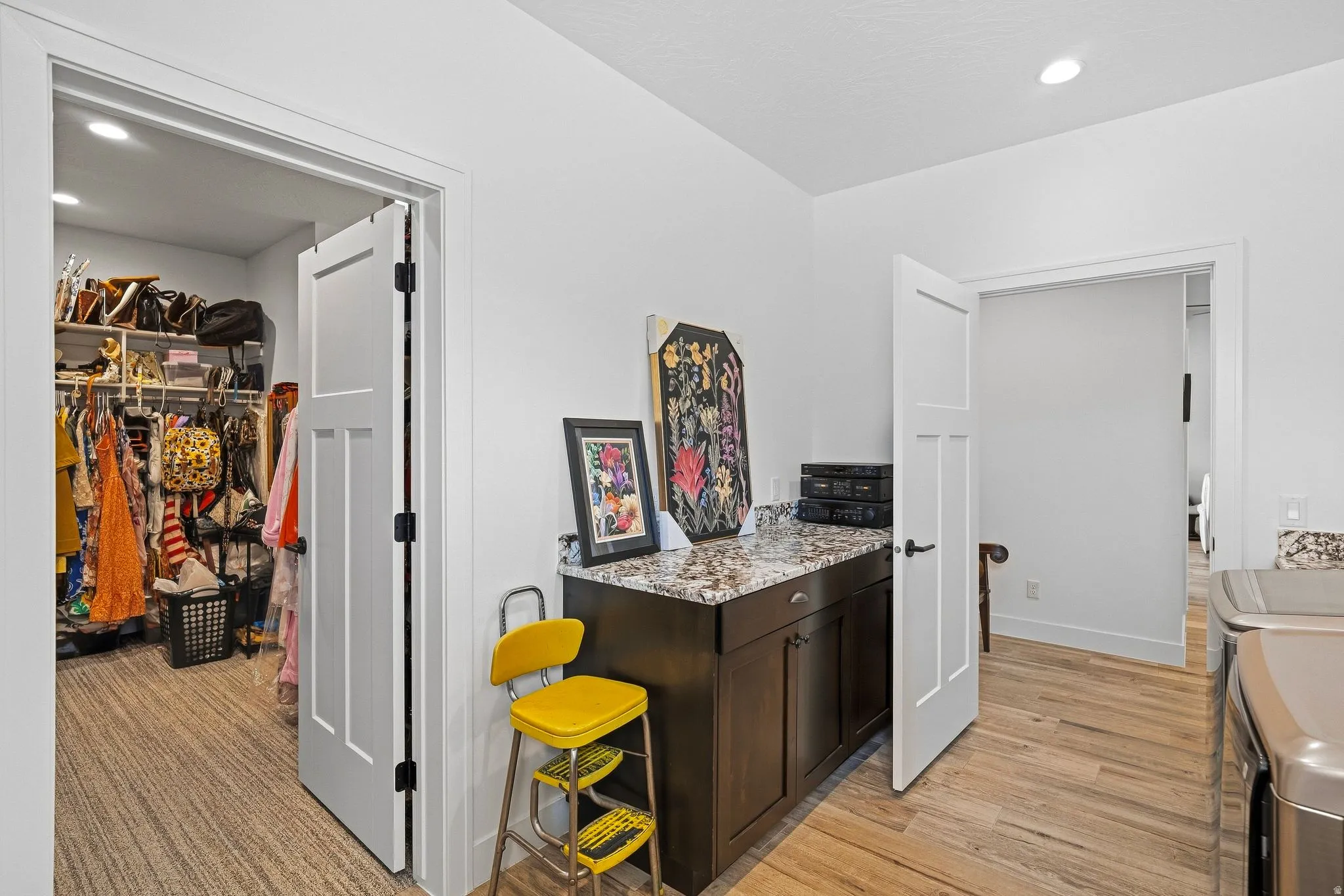 Wood-finish flooring, white paneled doors, dark wood cabinetry with a speckled countertop, and recessed lighting