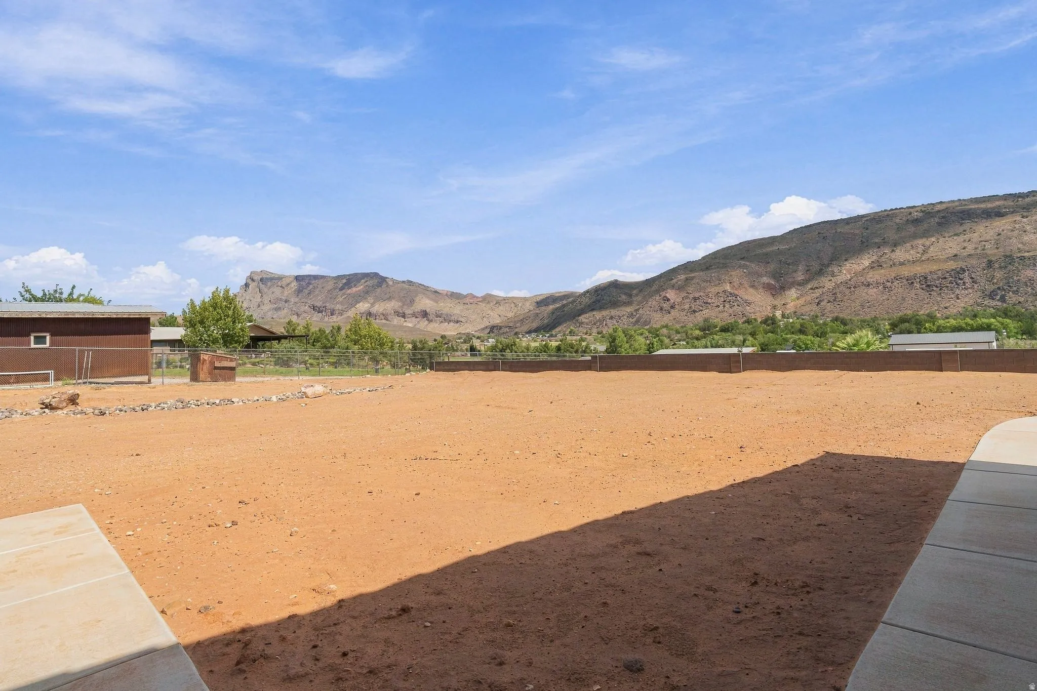 Expansive undeveloped lot with perimeter fencing and a concrete patio