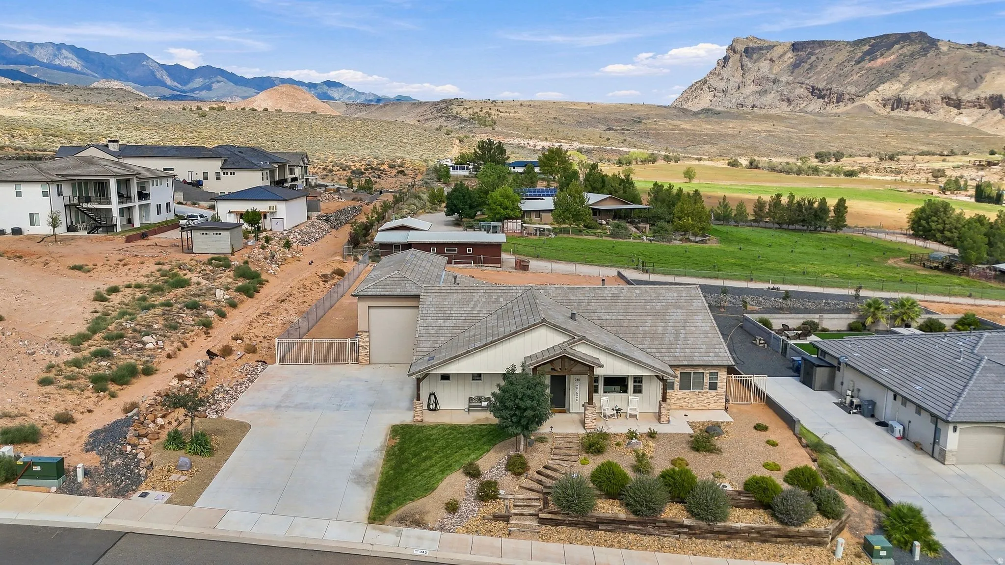 Contemporary ranch-style residence featuring a stone and stucco exterior, an attached garage, a xeriscaped front yard with mature plantings, and a concrete driveway
