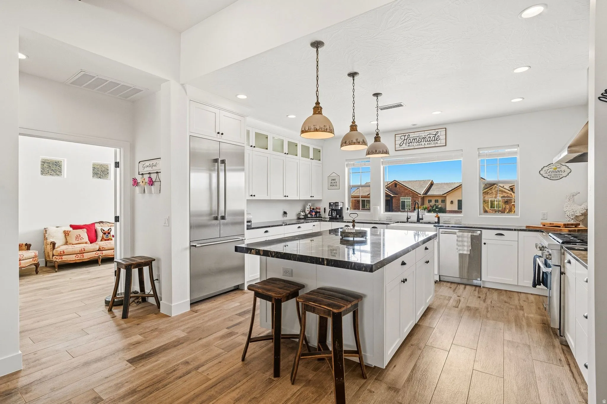Kitchen featuring white cabinetry, dark countertops, stainless steel appliances, a large central island, and wood-finish flooring