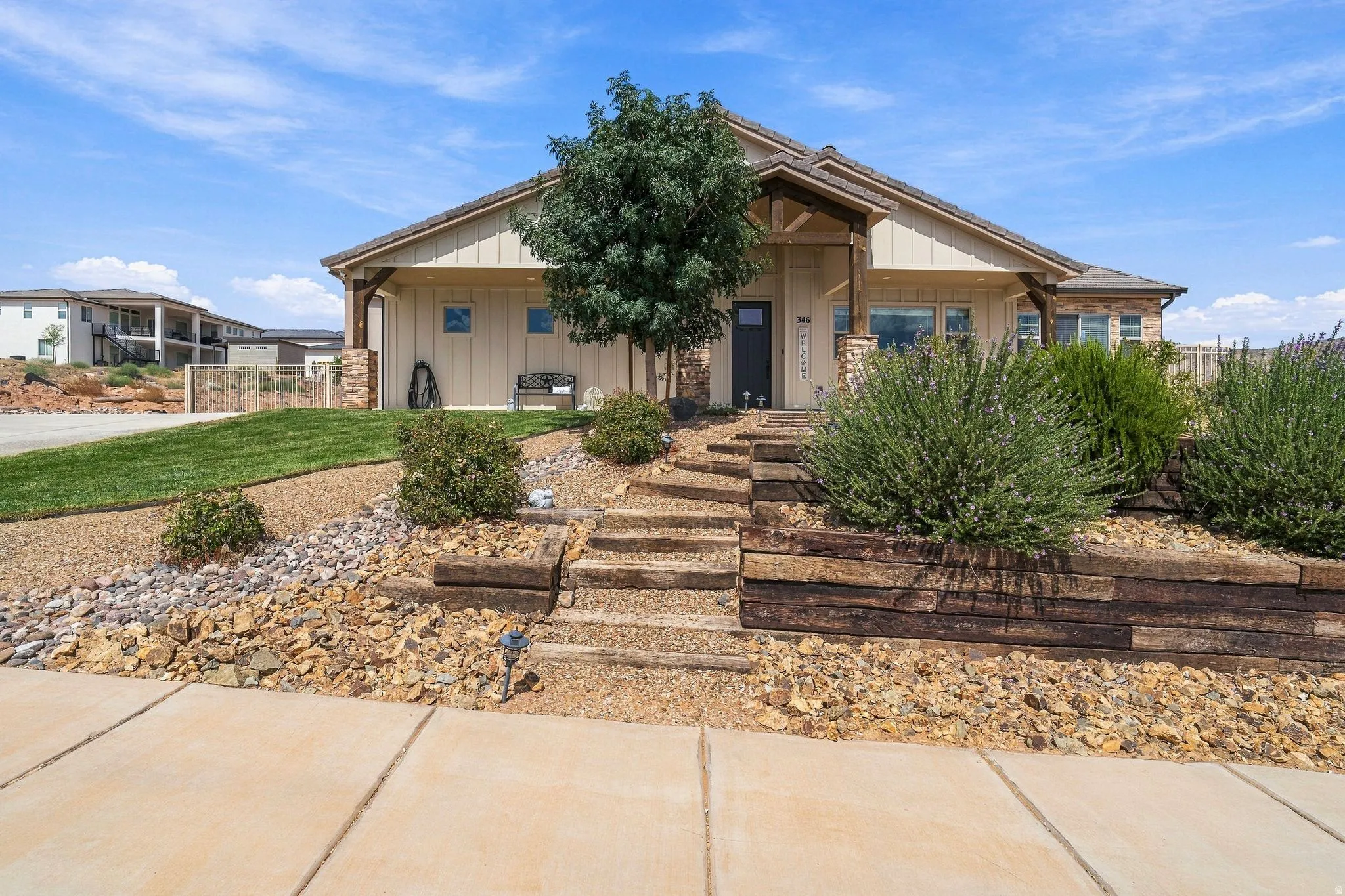 Inviting front entrance with a covered porch, stone column accents, and wood-toned siding