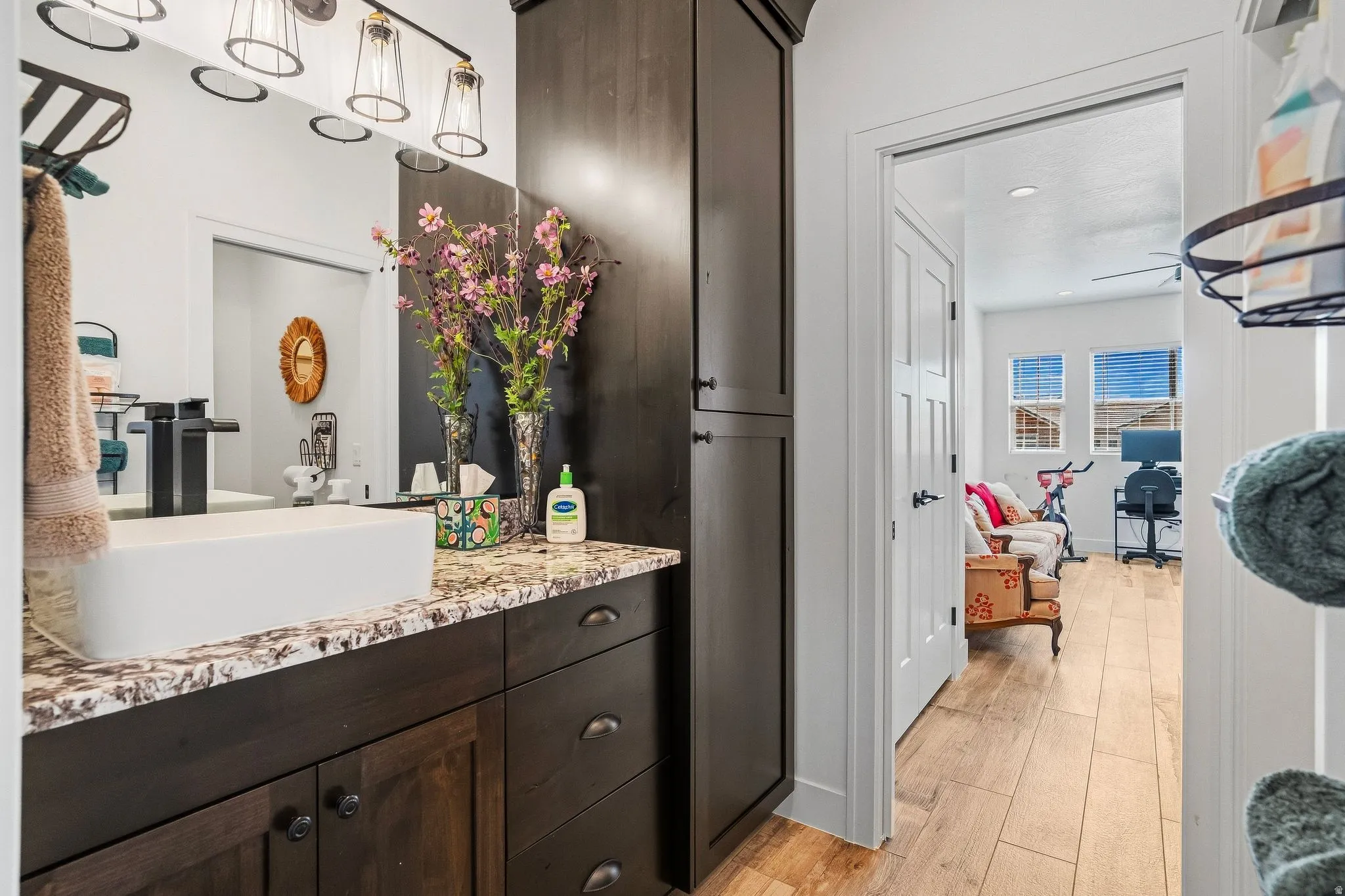 Dark wood-finish cabinetry with a vessel sink, a granite-style countertop, and a built-in storage cabinet